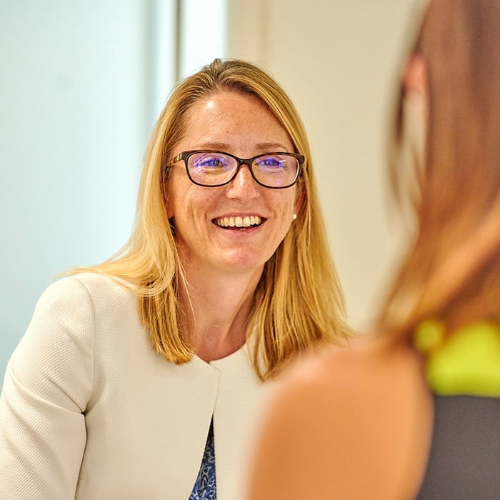 Amy Luke from BIE wearing glasses, wearing a cream blazer and smiling.