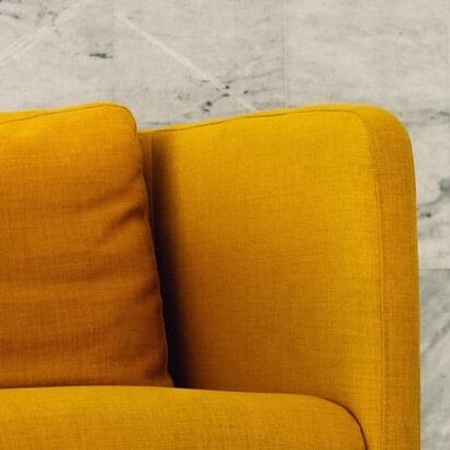 The corner of a yellow sofa, with a marble background.