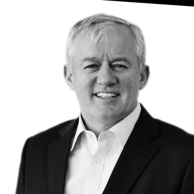 Steve Callaghan smiling at the camera wearing a pink shirt and dark blue blazer.