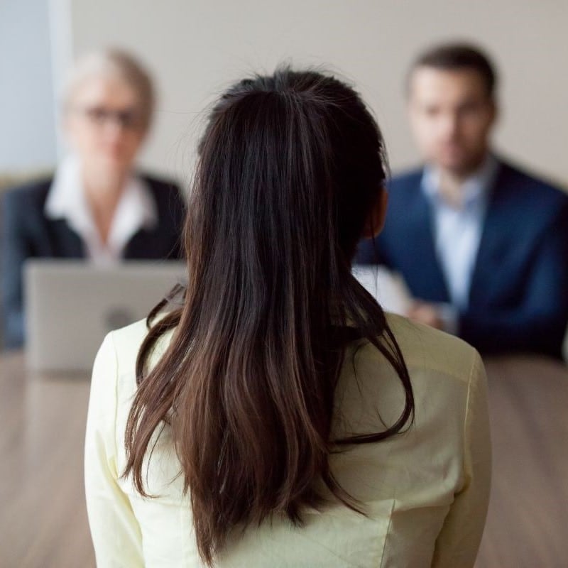 A candidate sat in front of two senior business people interviewing them.