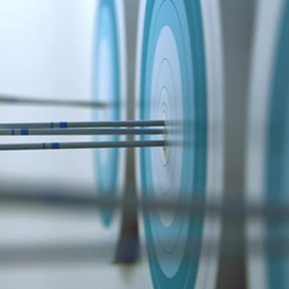 A closeup of arrows sitting in a target after having been shot.