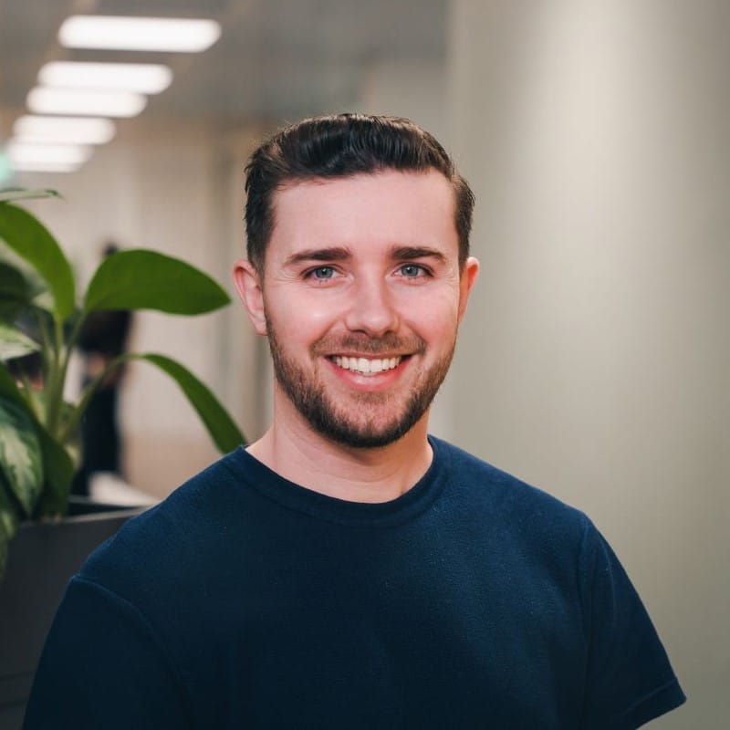 Matt Kaye standing in an office next to green plants.